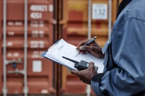 Close up of male worker writing on clipboard