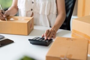Woman Works with Boxes, Calculator, and Pen